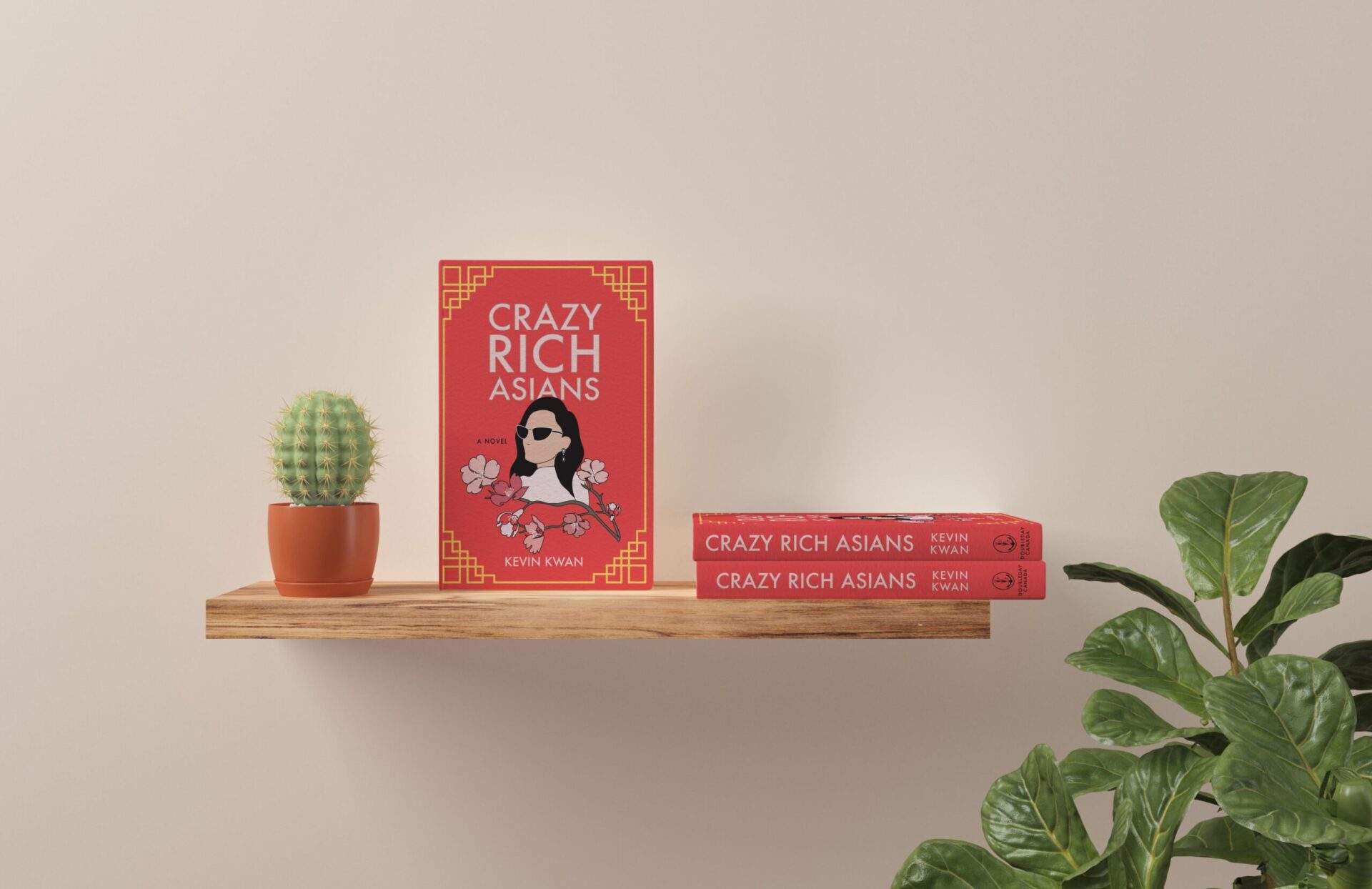 A red book, "Crazy Rich Asians," stands prominently on a wooden shelf, while two other books lie adjacent on the same shelf.